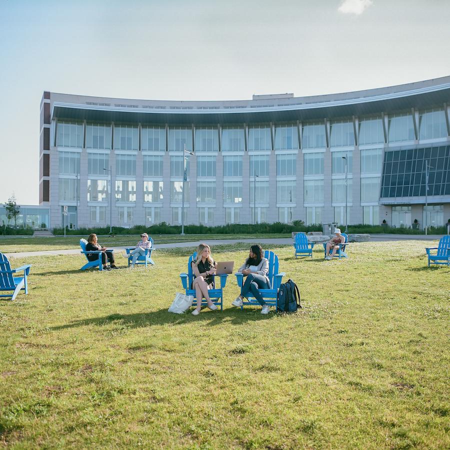Student on Beacon Lawn in Blue Chairs