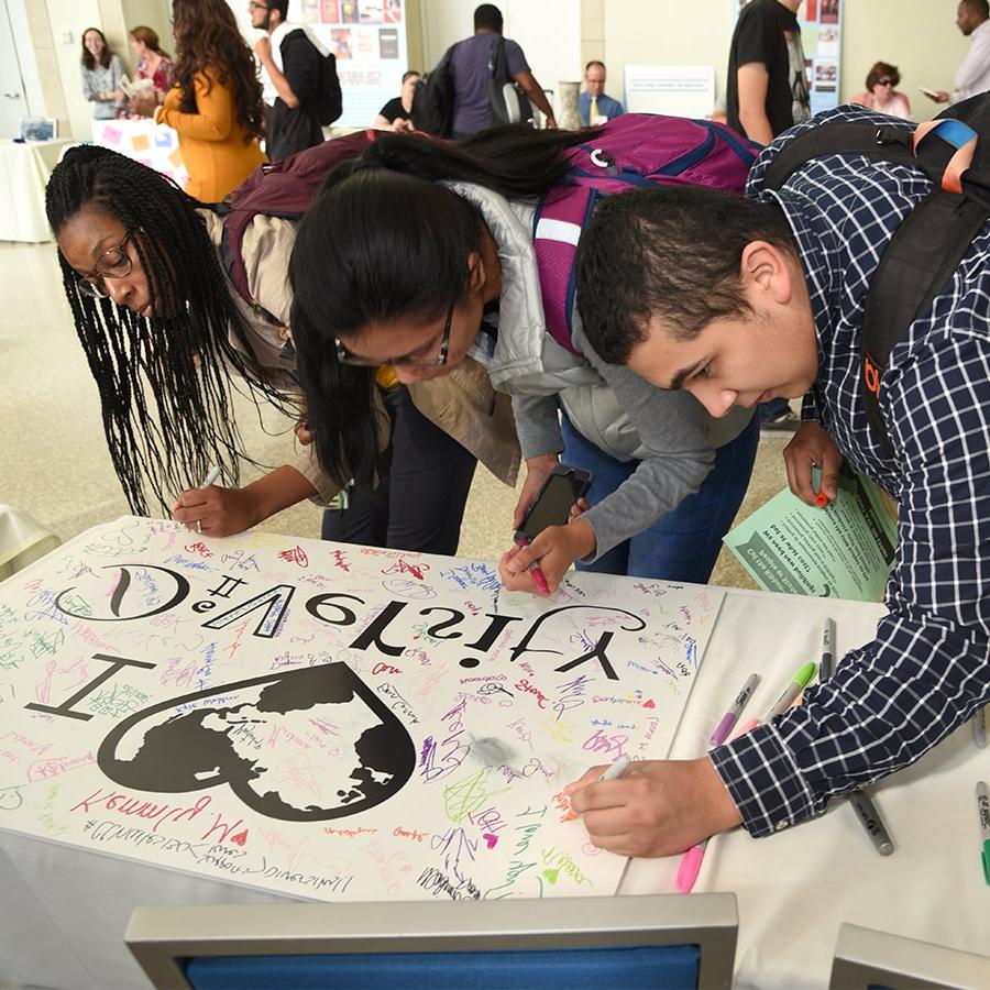 Students sign diversity heart poster.