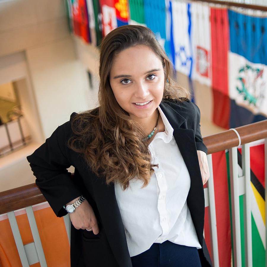 International student poses in front of flags at Campus Center.