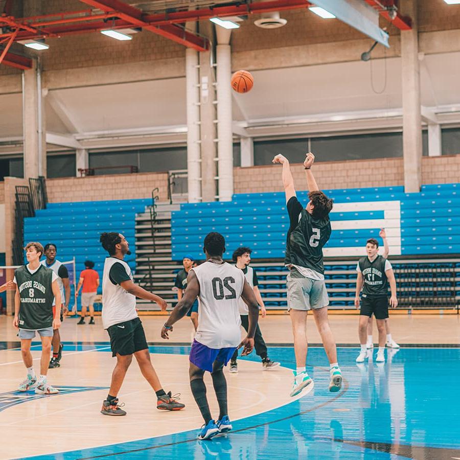 Students play basketball inside gym.